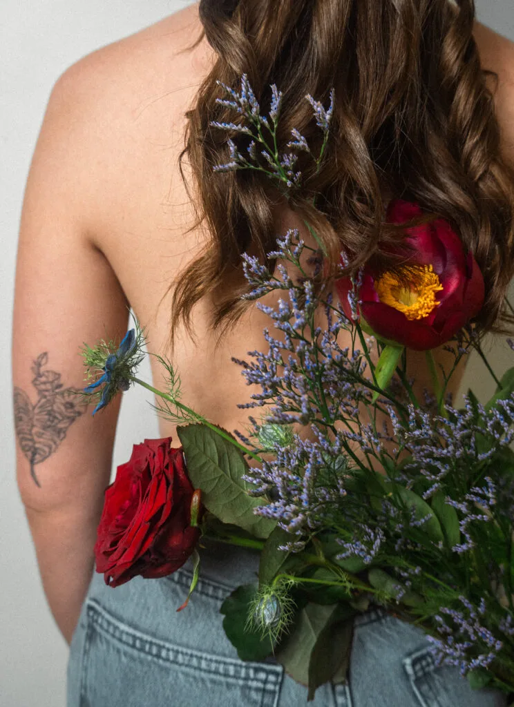 Femme dissimulée derrière un bouquet de fleurs – photo artistique boudoir