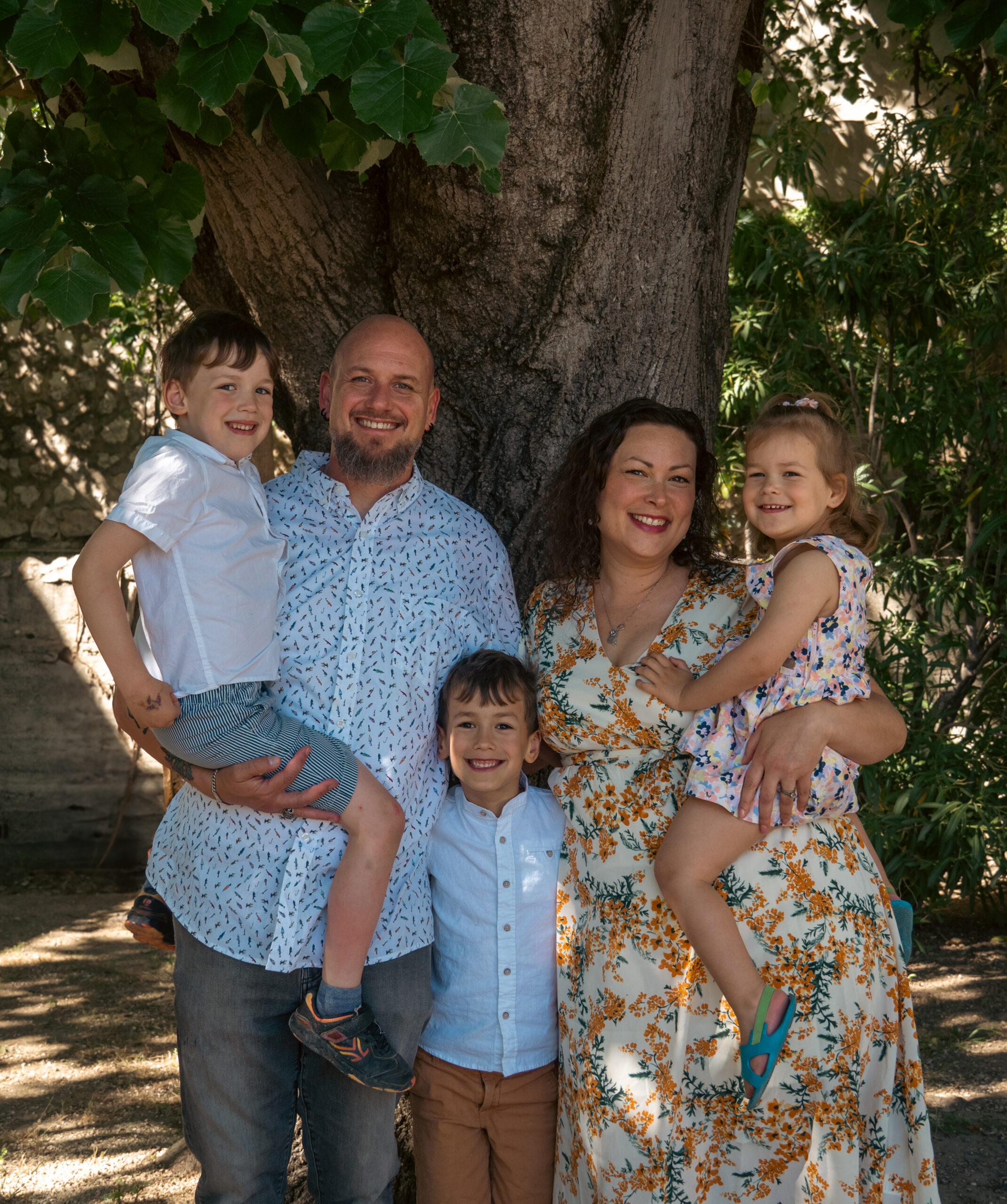 Toute la famille souriant devant un arbre pendant une séance photo famille à Marseille